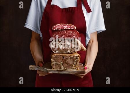 Donna irriconoscibile tiene il tavolo in mano con il rotolo di carne di maiale bollita, il rotolo di lingua di manzo e la salsiccia fatta in casa Foto Stock