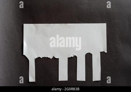 Foglio bianco vuoto con linguette a strappo su sfondo grigio. Foglio di carta sgualcito con strisce irregolari. Non tutti i segnalibri a strappo. Via A. Foto Stock