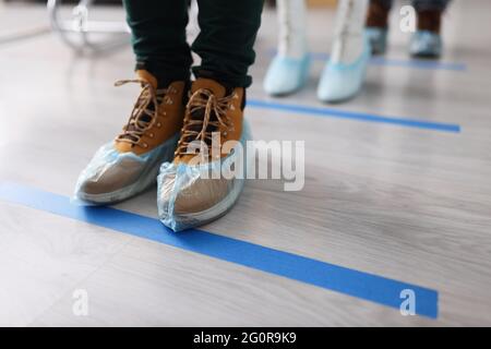 Persone in copriscarpe sui loro piedi in linea vicino linea blu closeup linea Foto Stock