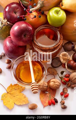 miele, mele e frutti autunnali su sfondo bianco Foto Stock