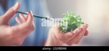 Lavoratore medico che tiene un modello di coronavirus e una siringa. Foto Stock