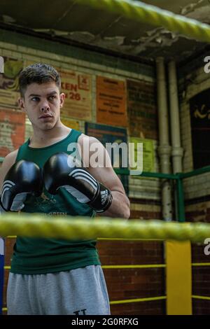 Giovane atletico che si prepara per le competizioni di pugilato, la difesa di addestramento e gli attacchi nel randello di boxe. Foto Stock