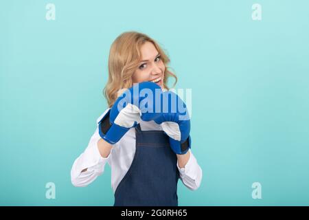 donna in grembiule e guanti di boxe. successo casalingo. lavoro domestico e domestico. Foto Stock