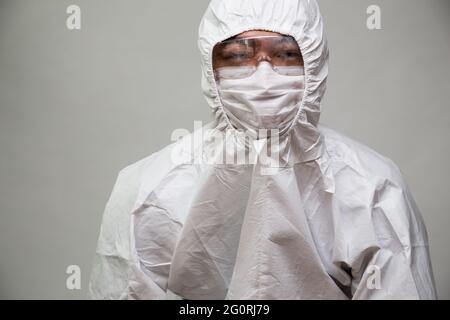 Ritratto di medico o infermiere asiatico in dispositivi di protezione individuale o tuta PPE e indossare maschera facciale e occhiali Foto Stock