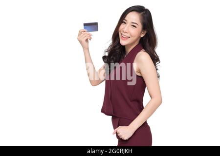 Ritratto di una giovane donna felice in abito rosso che tiene atm o carta di debito o di credito e utilizzando per lo shopping online spendere un sacco di soldi isolati su W. Foto Stock