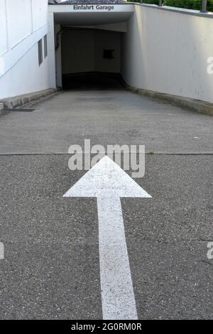 Ingresso a un parcheggio sotterraneo con una freccia bianca che indica la direzione. Foto Stock