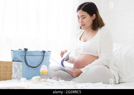 Donna incinta preparazione hospital bag e lista di controllo per la realizzazione di un piano di nascita da un ospedale che ha cure prenatali per la sicurezza del bambino, Pianificazione prena Foto Stock