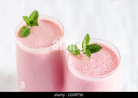 Primo piano di due bicchieri di frullato di fragola con guarnitura alla menta. Foto Stock