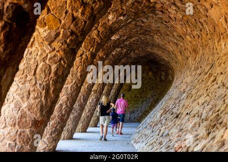 Barcellona, Spagna - 5 ottobre 2018: Passeggiata turistica per famiglie su un sentiero colonnato sotto la collina di Park Guell, l'edificio d'arte e il parco di Gaudi. Foto Stock