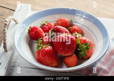 Fragole naturali mature in una ciotola su un tavolo di legno Foto Stock