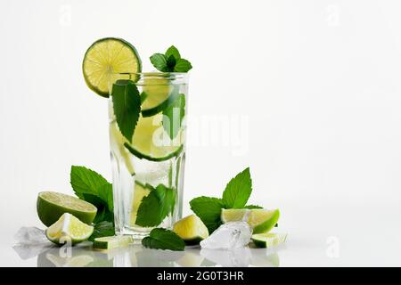 Fresco cocktail mojito fatto in casa in un bicchiere alto con lime, menta e ghiaccio su sfondo bianco, spazio copia. Foto Stock