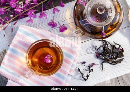 Tè alle erbe fatto da fireweed conosciuto come sally fiorente in teiera e tazza, vista dall'alto. Foto Stock