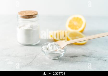 Pulitori naturali eco-friendly, vaso con bicarbonato di sodio, limone e cucchiaio di legno su sfondo di marmo tavolo. Ingredienti biologici per la pulizia fatta in casa Foto Stock