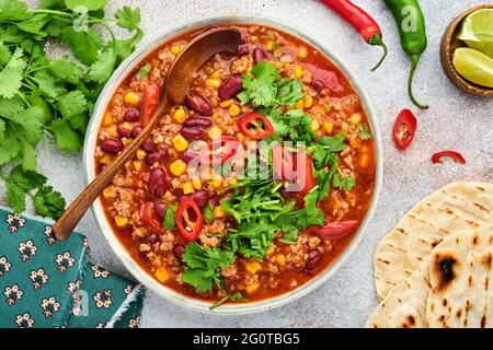 Zuppa messicana di fagioli neri con carne tritata, pomodoro, coriandolo, avocado e verdure stufate su un fondo grigio chiaro di ardesia, pietra o cemento. Tradizione Foto Stock