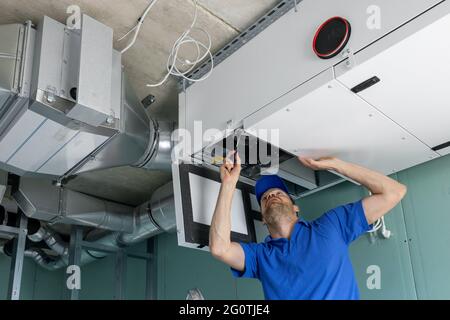 il tecnico hvac installa il sistema di ventilazione con recupero di calore condotto con recupero Foto Stock