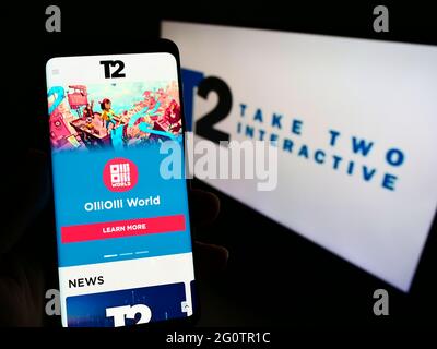 Persona che tiene smartphone con sito web della società di videogiochi Take-Two Interactive Software Inc su schermo con logo. Mettere a fuoco il centro del display del telefono. Foto Stock