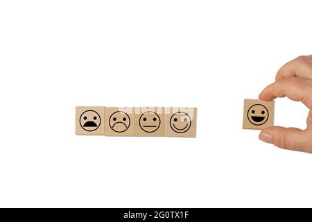 Una mano che tiene un cubo con il simbolo di un sorriso felice, con 4 cubetti sul lato che simboleggiano l'intera scala di soddisfazione del cliente. Foto Stock