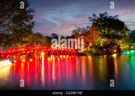 Hanoi Red Bridge di notte. Il ponte in legno dipinto di rosso sul lago Hoan Kiem collega la riva e l'isola di Jade su cui si trova il tempio di Ngoc Son Foto Stock