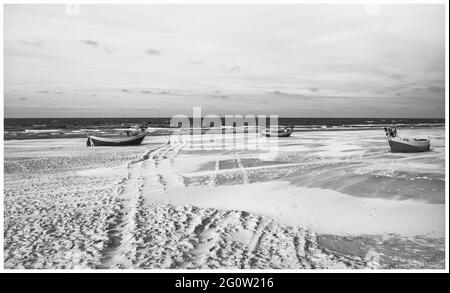 Barche da pesca sulla costa dell'Osstsee sulla spiaggia in Polonia in un aspetto malinconico bianco e nero. Spiaggia sul Mar Baltico con barche da pesca. Foto Stock