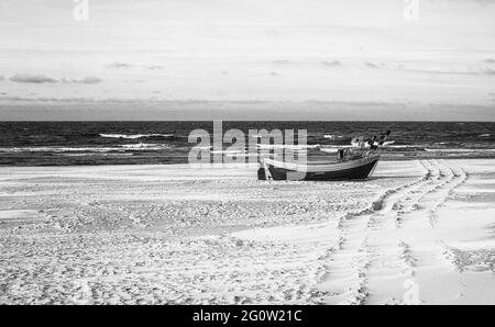 Barche da pesca sulla costa dell'Osstsee sulla spiaggia in Polonia in un aspetto malinconico bianco e nero. Spiaggia sul Mar Baltico con barche da pesca. Foto Stock