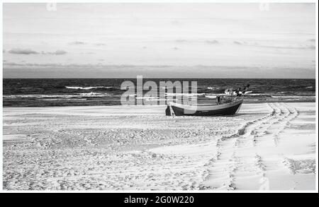 Barche da pesca sulla costa dell'Osstsee sulla spiaggia in Polonia in un aspetto malinconico bianco e nero. Spiaggia sul Mar Baltico con barche da pesca. Foto Stock