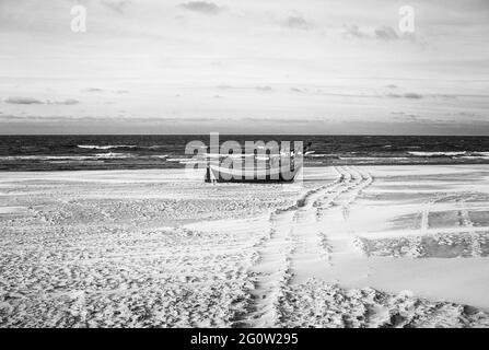 Barche da pesca sulla costa dell'Osstsee sulla spiaggia in Polonia in un aspetto malinconico bianco e nero. Spiaggia sul Mar Baltico con barche da pesca. Foto Stock