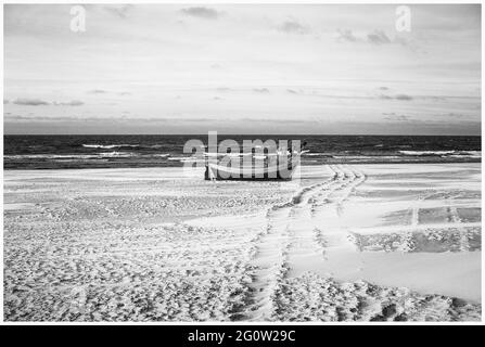 Barche da pesca sulla costa dell'Osstsee sulla spiaggia in Polonia in un aspetto malinconico bianco e nero. Spiaggia sul Mar Baltico con barche da pesca. Foto Stock