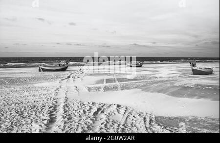 Barche da pesca sulla costa dell'Osstsee sulla spiaggia in Polonia in un aspetto malinconico bianco e nero. Spiaggia sul Mar Baltico con barche da pesca. Foto Stock