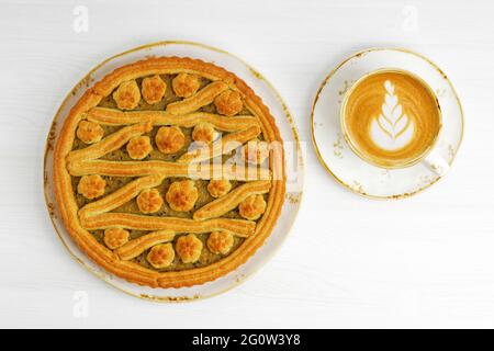 Torta al limone con uva spina fatta in casa e una tazza di cappuccino al caffè su un tavolo di legno bianco. Vista dall'alto. Foto Stock