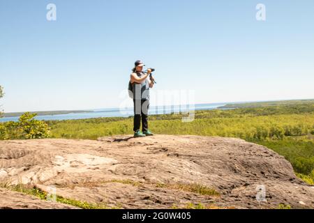 TOBERMORY, CANADA - 30 maggio 2021: Una donna scatta una foto di un belvedere nella baia georgiana - foto editoriale a tema turistico. Foto Stock