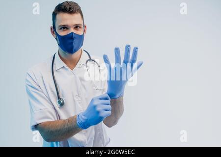 Medico maschile europeo che mette guanti in lattice Foto Stock