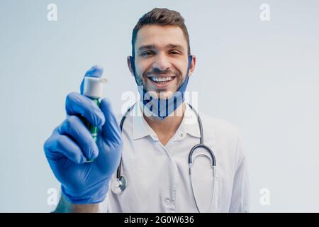 Sorridente medico di sesso maschile che mostra l'inalatore in studio Foto Stock