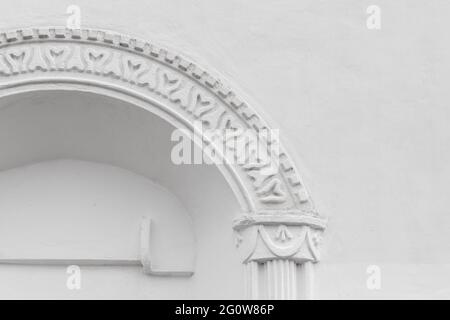 Sfondo architettonico con un arco in una parete bianca. Antica decorazione russa della facciata del tempio Foto Stock