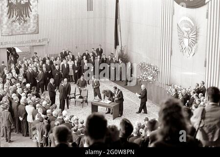 KN-29197 23 giugno 1963 viaggio del presidente John F. Kennedy in Europa. Il presidente Kennedy firma il Libro d'Oro durante una cerimonia di benvenuto a Colonia data dall'Oberburgermeister Theo Burauen. Il presidente Kennedy è circondato da un gruppo di ospiti tra cui il cancelliere della Germania occidentale Konrad Adenauer (parzialmente nascosto). Sezioni del Consiglio, Colonia Rathus, Colonia, Germania. Si prega di credito 'Robert Knudsen. Fotografie della Casa Bianca. John F. Kennedy Presidential Library and Museum, Boston' Foto Stock