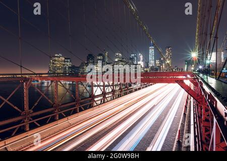 Automobili che guidano sull'autostrada sotto il ponte sospeso nella città di notte Foto Stock