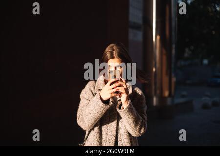 Giovane donna con smartphone in piedi in città Foto Stock