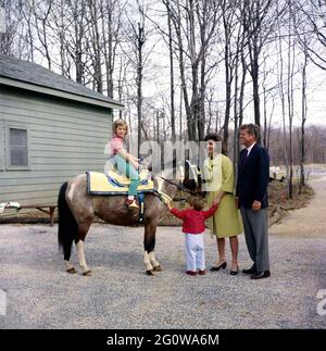 KN-C27672 31 Marzo 1963 Weekend al Camp David. Il presidente John F. Kennedy e la famiglia osservano Caroline Kennedy cavalcando un cavallo di nome "Macaroni" al Camp David. 'Macaroni' indossa una sella marocchina blu e oro, un regalo al presidente Kennedy di Re Hassan II La fotografia include: (L-R) Caroline Kennedy, John F. Kennedy, Jr., First Lady Jacqueline Kennedy, e il presidente Kennedy. Camp David, Maryland. Si prega di credito 'Robert Knudsen. Fotografie della Casa Bianca. John F. Kennedy Presidential Library and Museum, Boston' Foto Stock