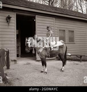 KN-C27677 31 marzo 1963 Weekend a Camp David. Caroline Kennedy pose seduta sul suo cavallo, 'Macaroni', la sella su Macaroni era un dono del re Hassan II di Morro. Camp David, Maryland. Si prega di credito 'Robert Knudsen. Fotografie della Casa Bianca. John F. Kennedy Presidential Library and Museum, Boston' Foto Stock