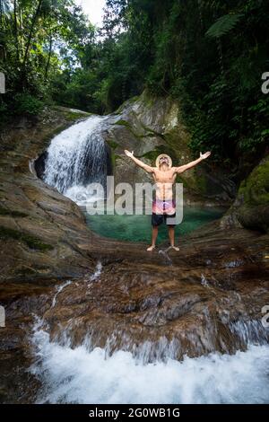 L'uomo gode di una bella piscina a cascata con acque cristalline della foresta pluviale Foto Stock