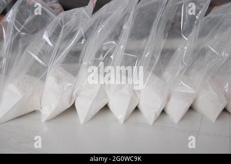 Un gran numero di bustine trasparenti riempite di polvere bianca. Polvere bianca confezionata in bustine piccole. Foto Stock