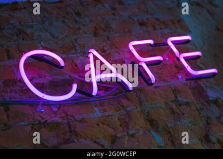 Lettere al neon, luminoso cartello caffè su una parete di mattoni da vicino. Foto Stock