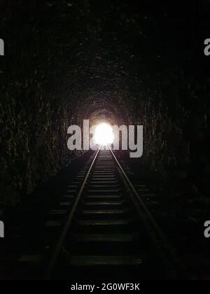 Vista interna di un tunnel ferroviario con binari che conducono in lontananza, prospettiva industriale e architettonica, luce e profondità spettacolari Foto Stock