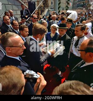 KN-C29294 23 giugno 1963 il presidente John F. Kennedy riceve un regalo dopo aver firmato il Libro d'Oro di Colonia durante il suo viaggio in Germania. La fotografia include: Il presidente Kennedy, il fotografo della Casa Bianca Cecil Stoughton (arroccato sulla scala), l'interprete Robert H. Lochner, i funzionari della città e gli spettatori. Rathaus, Bonn, Germania. Si prega di credito 'Robert Knudsen. Fotografie della Casa Bianca. John F. Kennedy Presidential Library and Museum, Boston' Foto Stock
