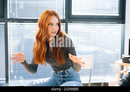 Primo piano di una giovane e attraente donna d'affari redhead che parla e discute di nuove idee con il team di business creativo Foto Stock