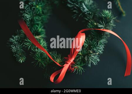 Corona di Natale con pino e nastro rosso. Idee per la decoriazione di natale. Sfondo di Natale. Foto Stock