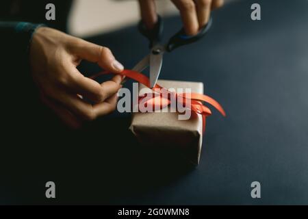 Confezione regalo in carta biologica su sfondo nero. Decorazioni natalizie fatte in casa e concetto regalo. Foto Stock