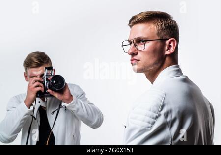 gli uomini gemelli dei fratelli osservano allo stesso modo usano la macchina fotografica vintage, fotografando Foto Stock