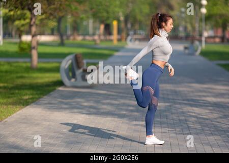 Foto della giovane donna. Allunga i muscoli delle gambe e si riscalda prima della gara. Concetto di sport e stile di vita sano. Foto Stock