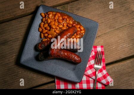 Bratwurst alla griglia con fagioli cowboy di pancetta sul tavolo da picnic Foto Stock