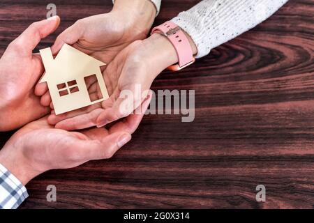 Primo piano della coppia mani che tiene la casa di carta - concetto di proprietà e famiglia Foto Stock